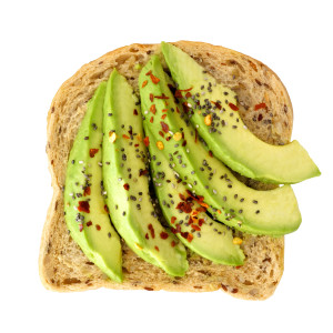 Open avocado sandwich with chia seeds and seasoning on whole grain bread isolated on a white background